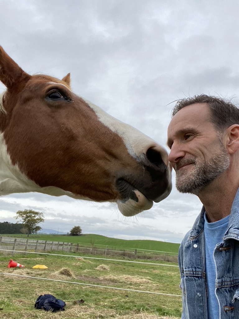 Steve Mullan face to face with a chestnut horse in a Waikato paddock